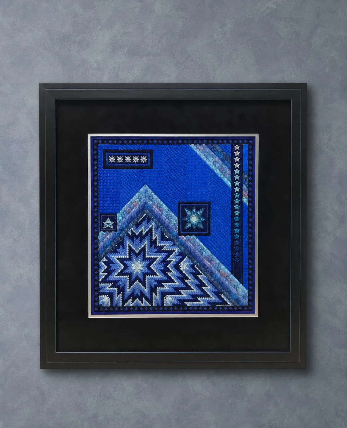 Blue geometric needlepoint in a black frame